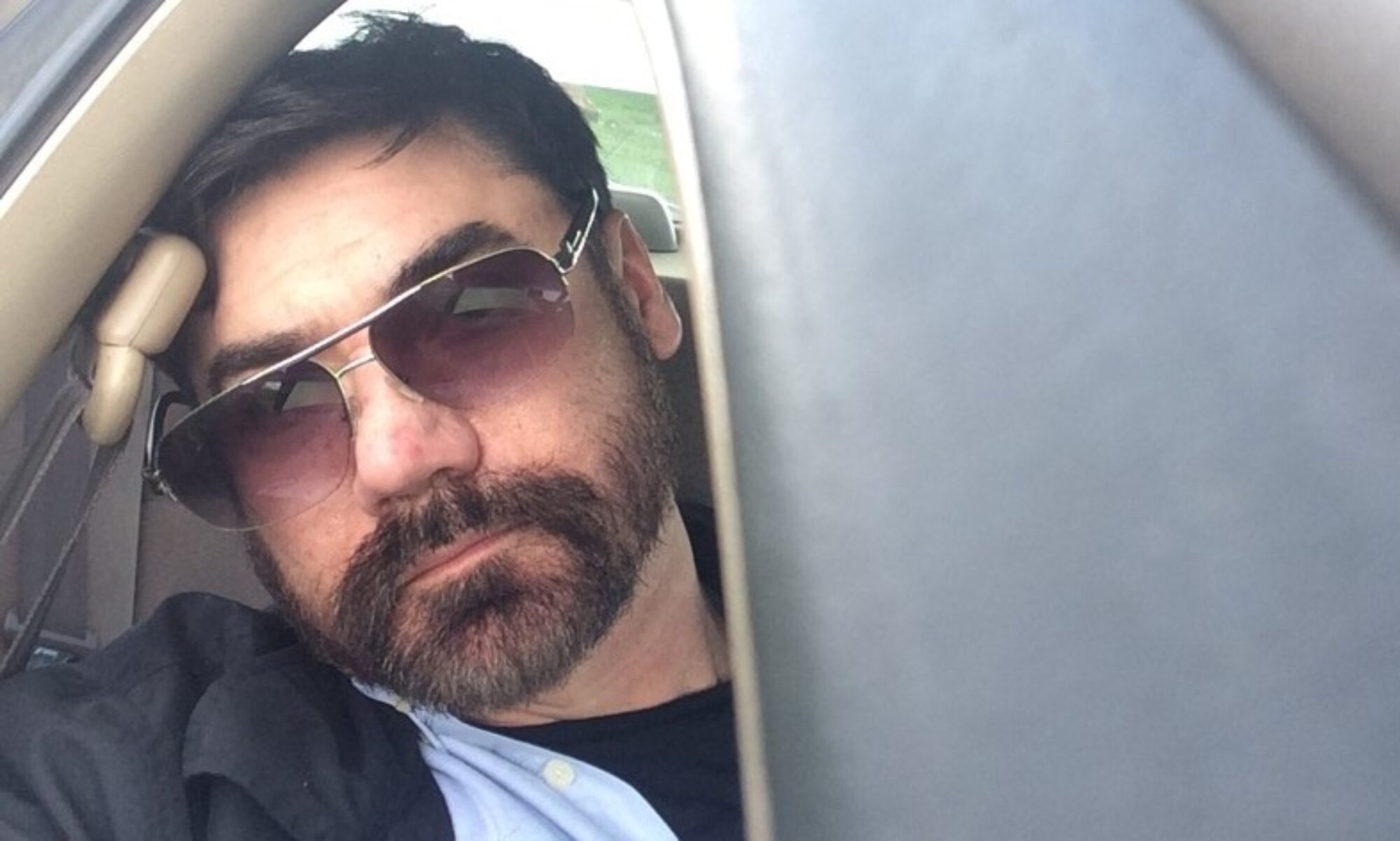 mike wearing shades looking out the window of a car